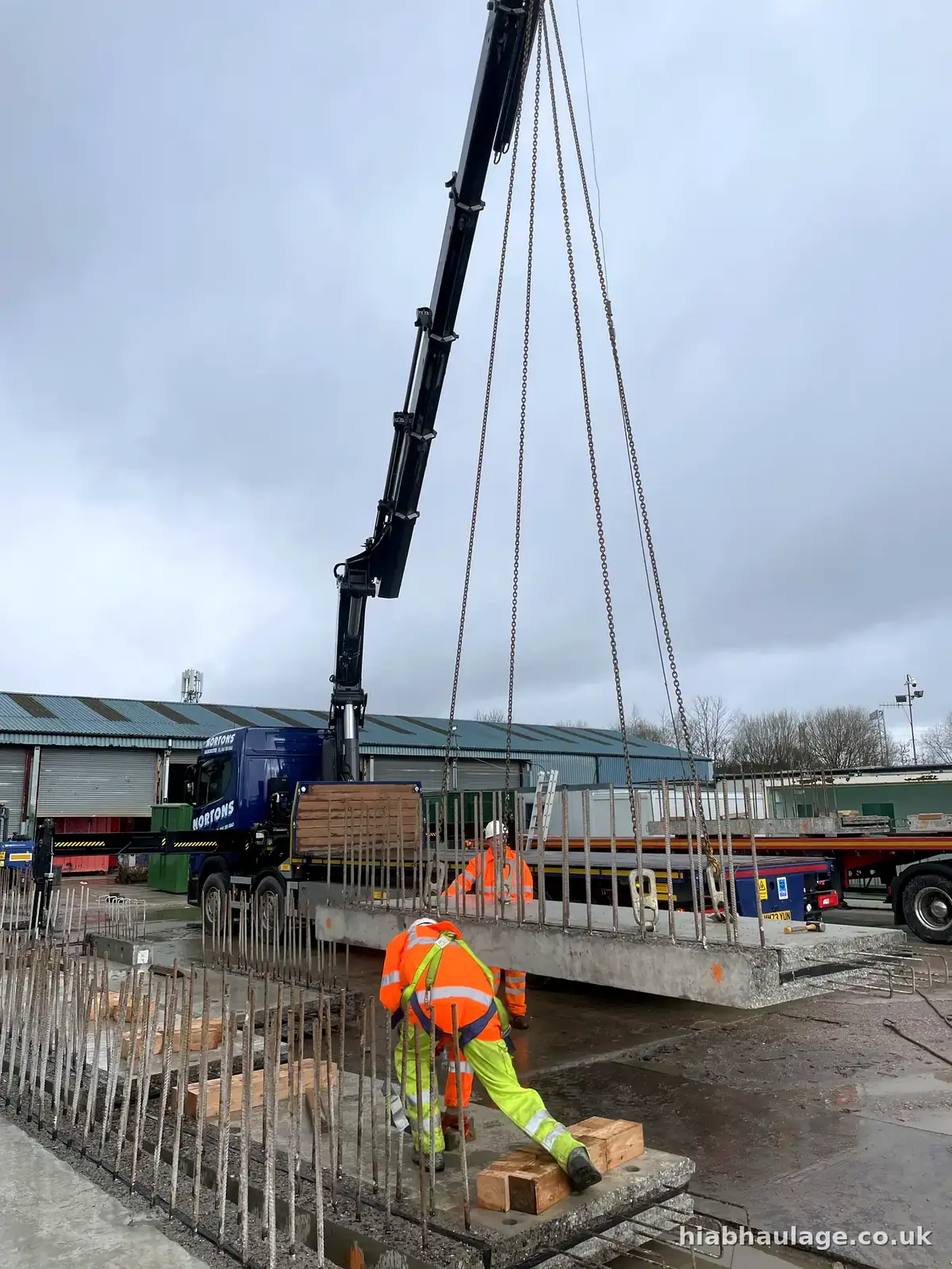 Crew positioning a precast concrete slab as it is lowered Crew positioning a precast concrete slab as it is lowered
