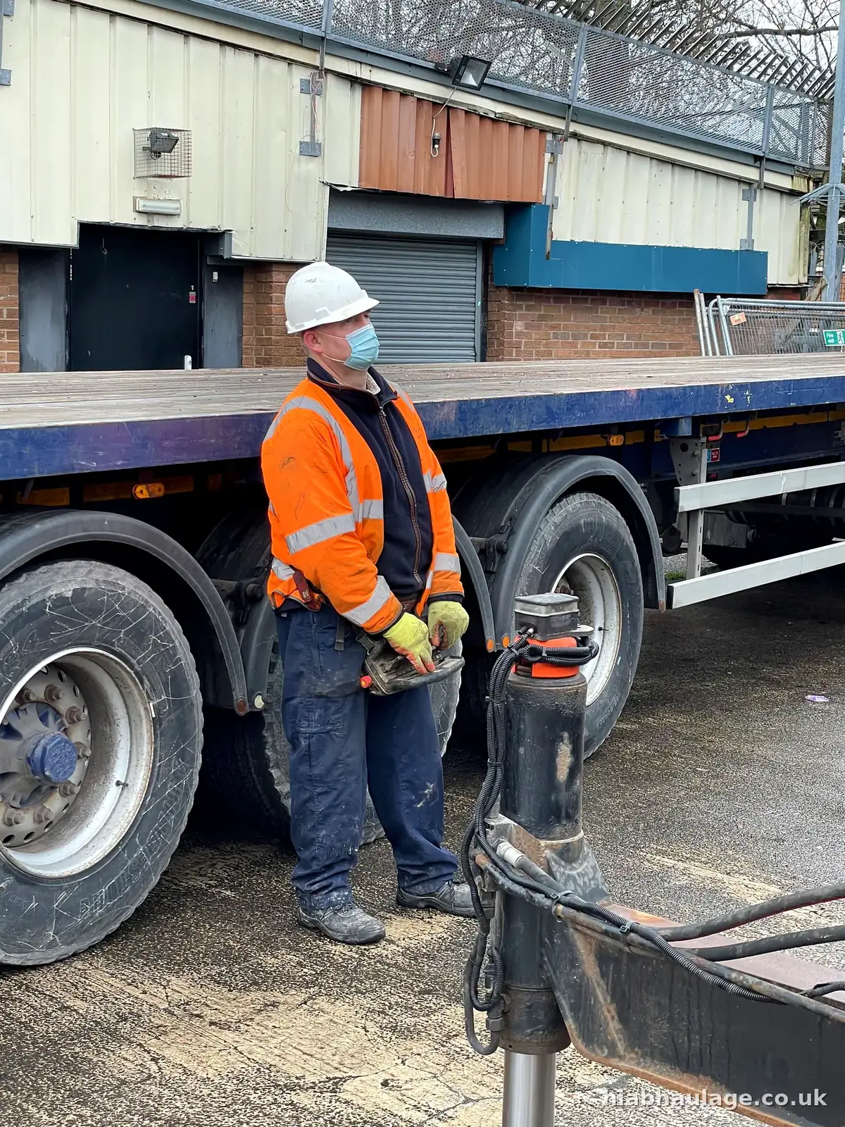 Driver working the HIAB controls beside the flatbed