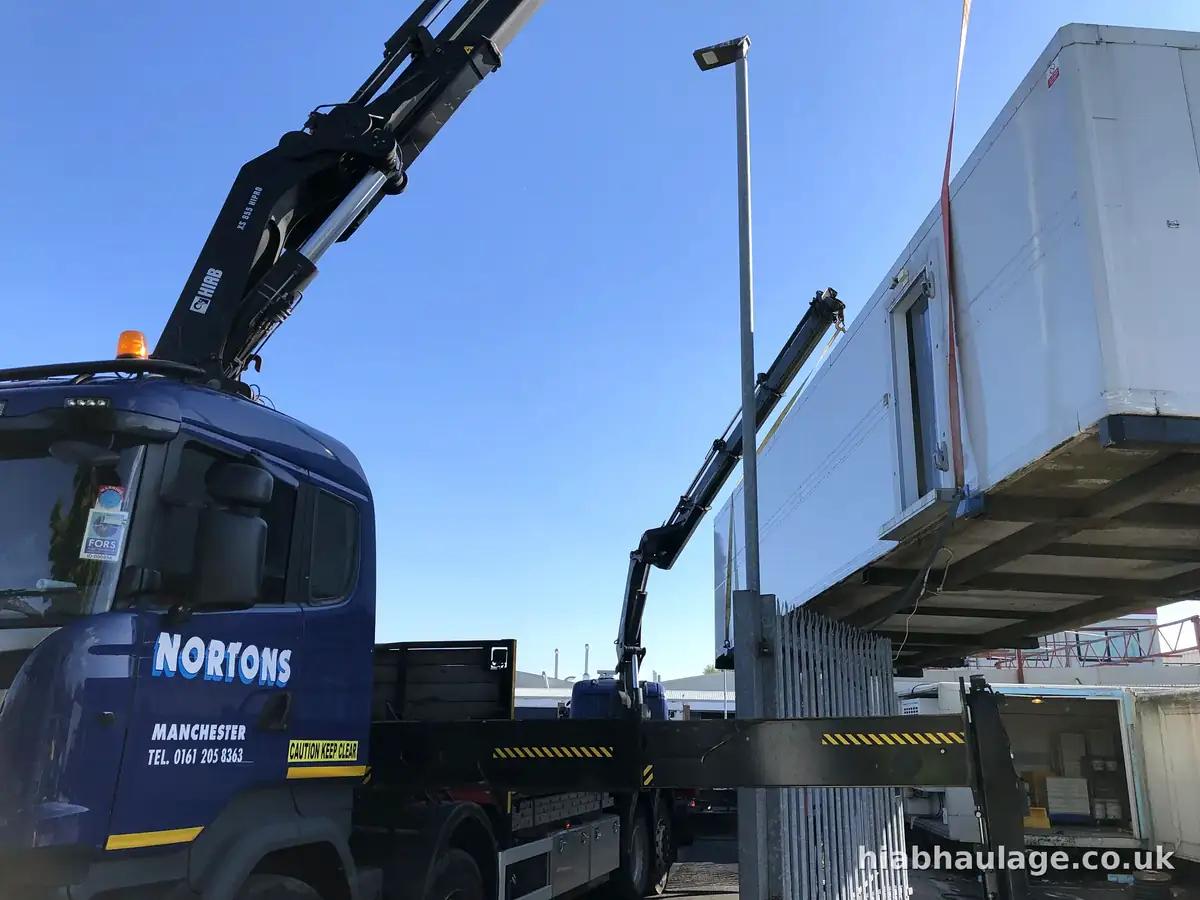 Two HIABs lifting a long white unit