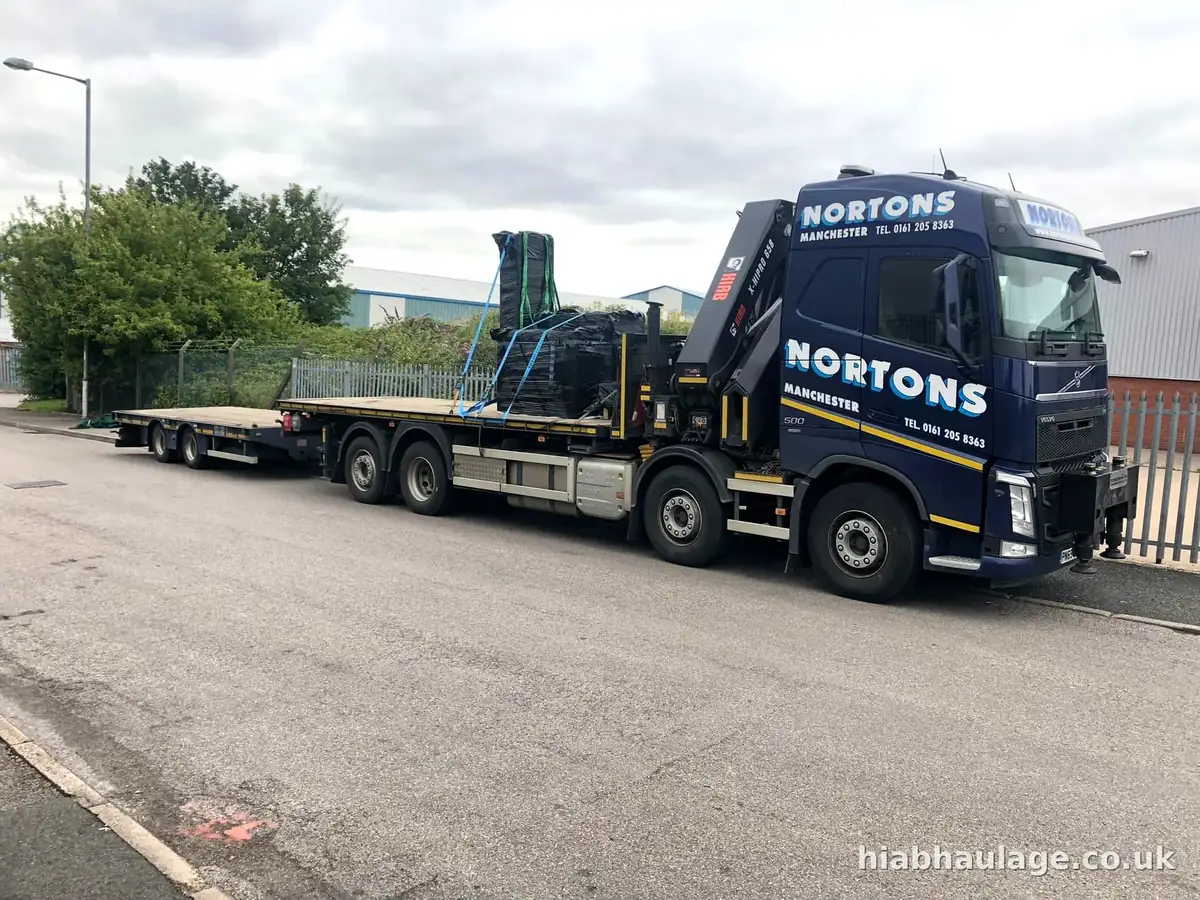 Volvo HIAB and trailer carrying wrapped machinery along an industrial road