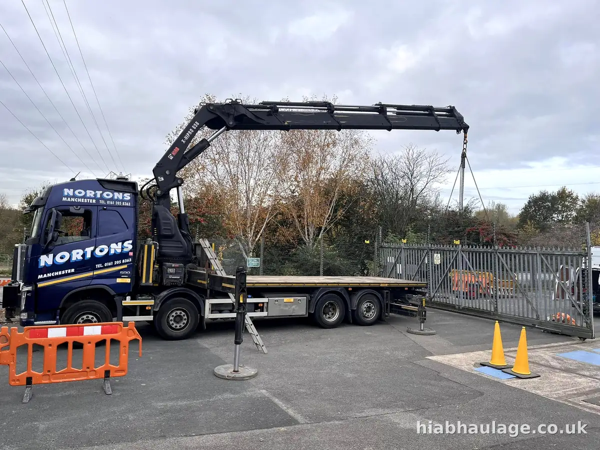 Rigid HIAB with stabilisers down and its lifting arm fully extended in a gated yard