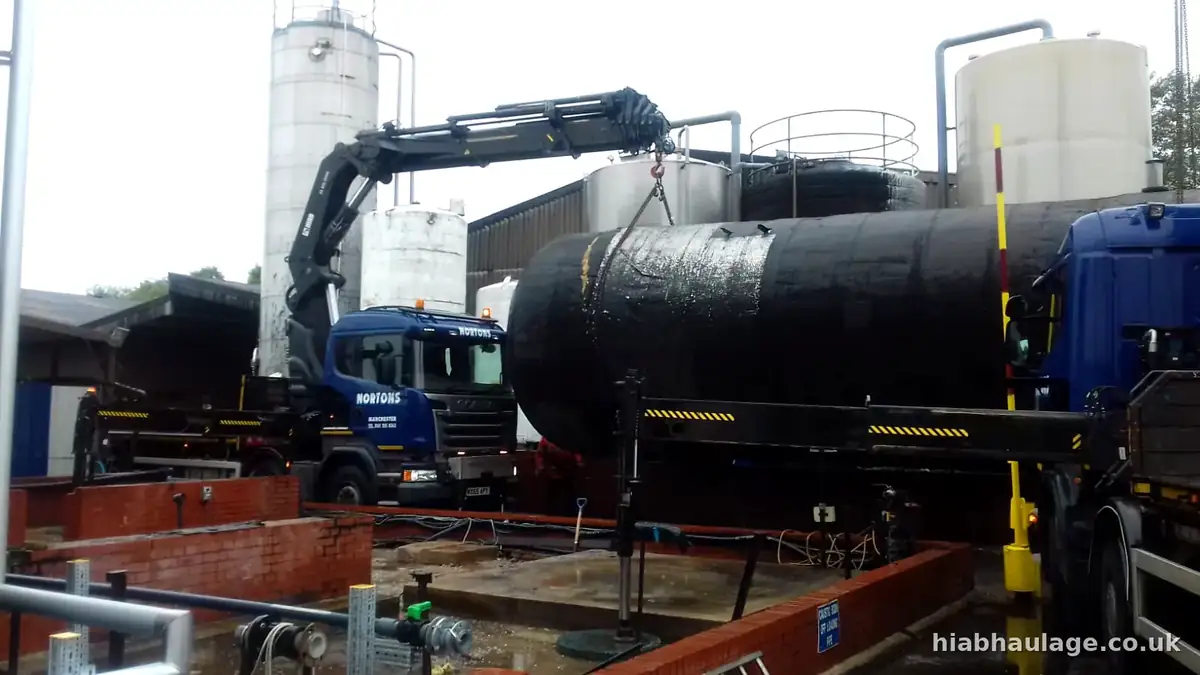 HIAB lifting a black tank at an industrial site