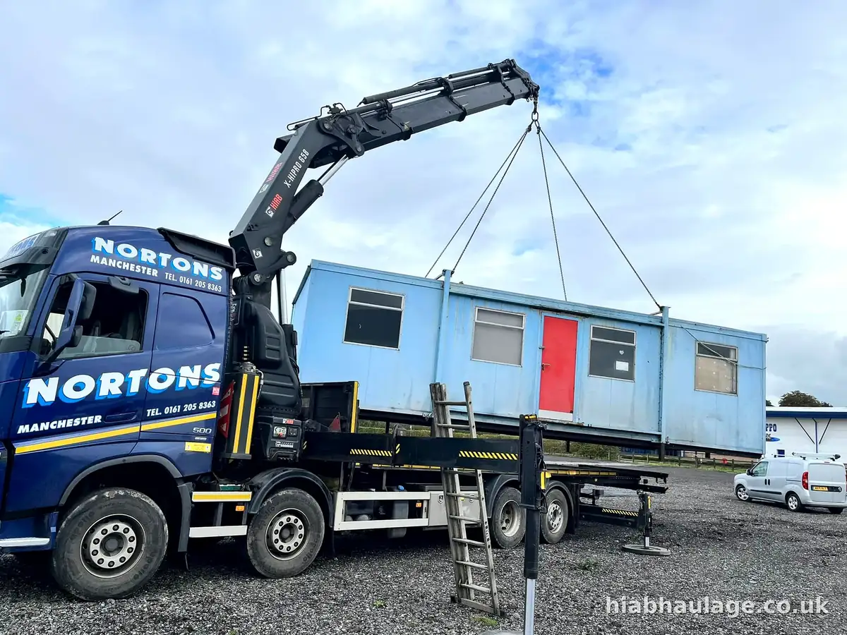 HIAB lifting a blue cabin with the slinger on a ladder