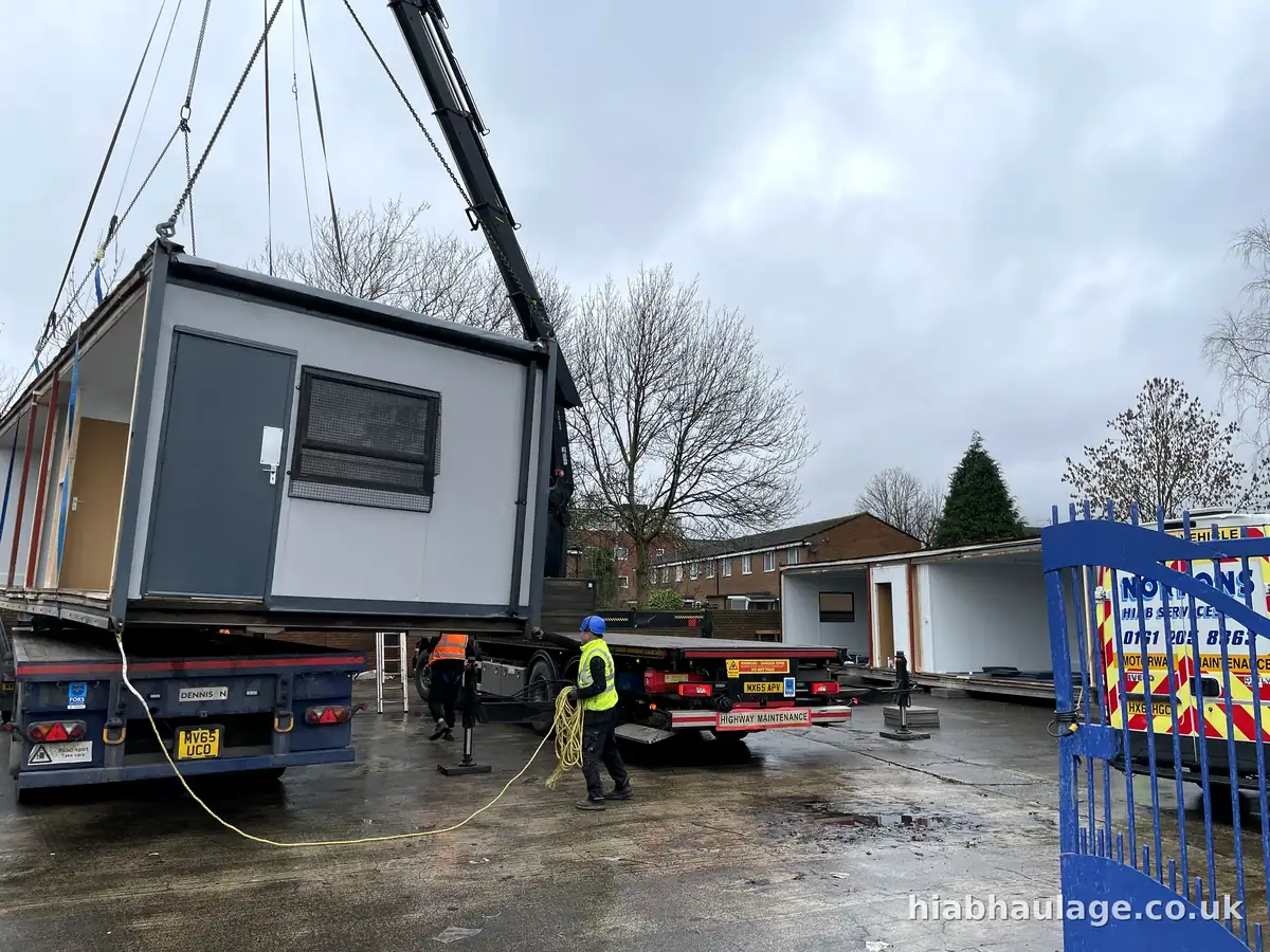 HIAB lifting a modular section from a trailer, crew guiding HIAB lifting a modular section from a trailer, crew guiding