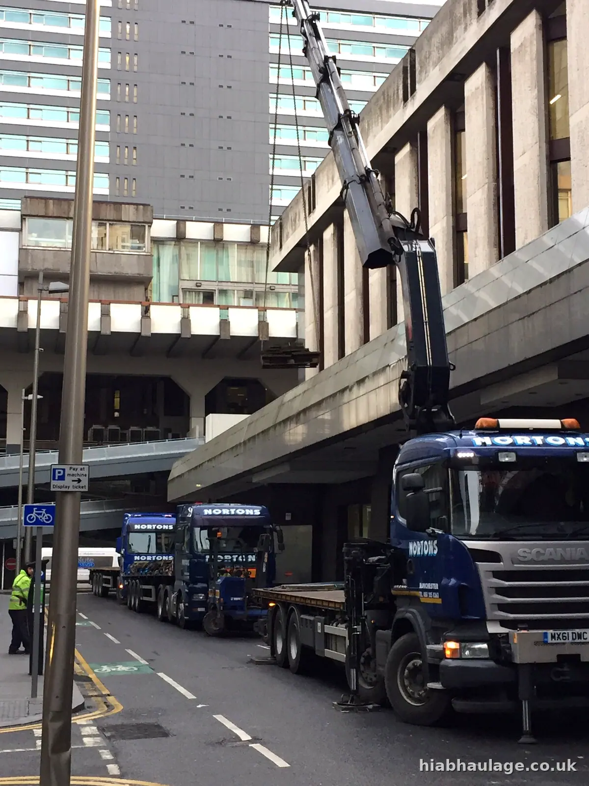 HIAB lorry lifting beside a walkway at a city tower