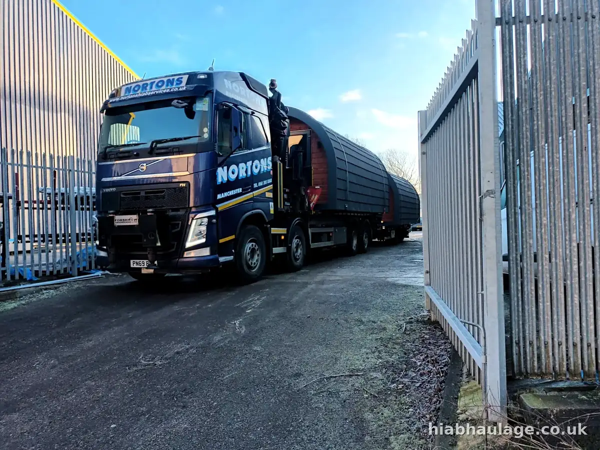 Volvo HIAB and trailer with timber pods leaving through site gates Volvo HIAB and trailer with timber pods leaving through site gates