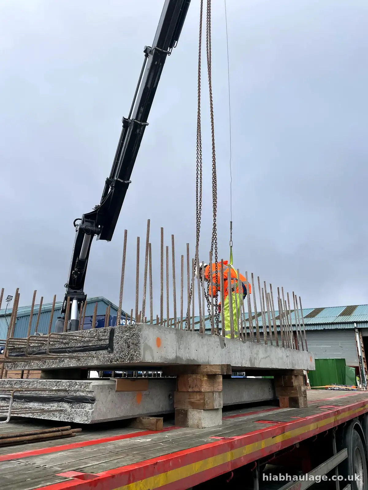 Precast slab with reinforcing bars on a flatbed, slinger alongside Precast slab with reinforcing bars on a flatbed, slinger alongside
