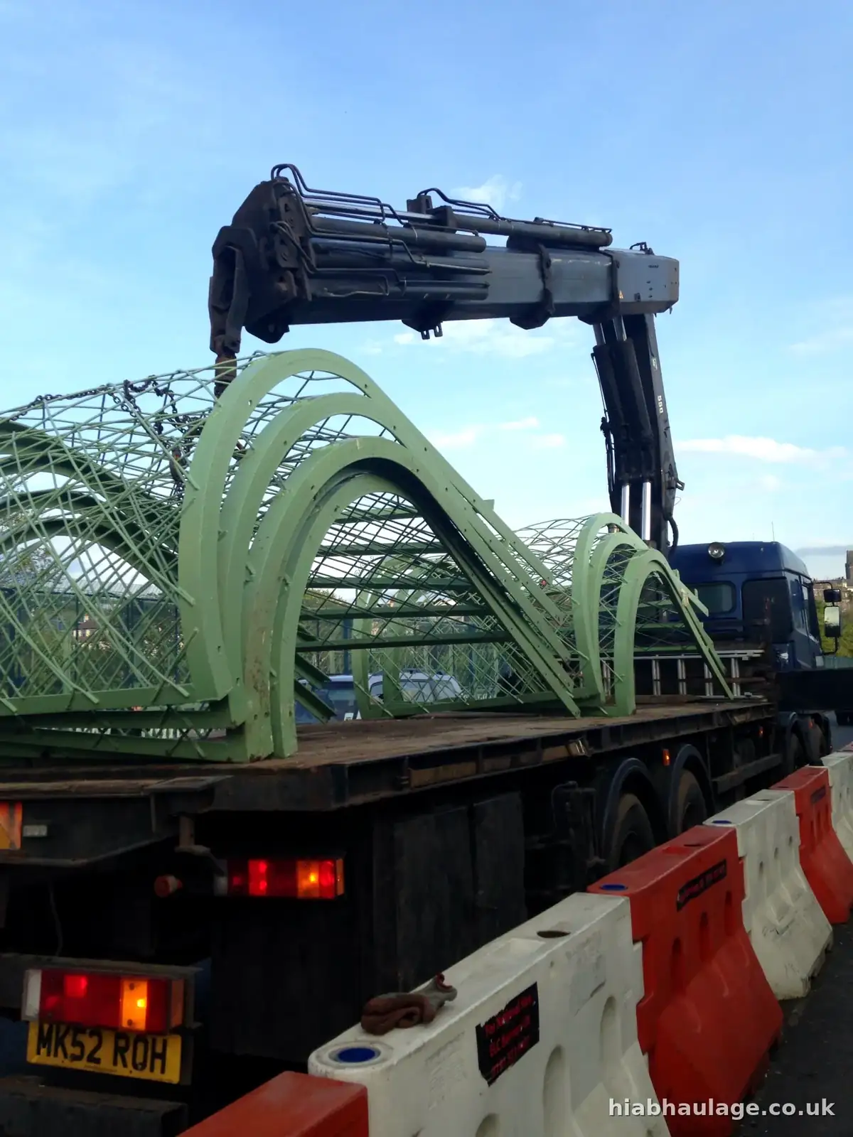 Steel arch sections on a rigid HIAB beside traffic barriers Steel arch sections on a rigid HIAB beside traffic barriers