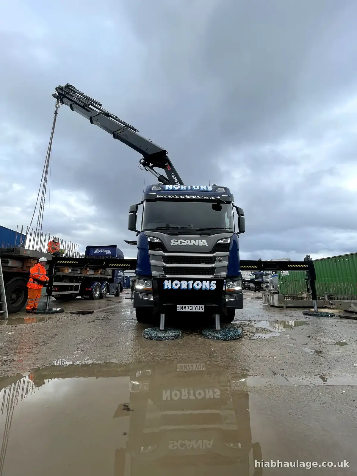 Rigid HIAB with stabilisers down lifting precast concrete in a wet yard Rigid HIAB with stabilisers down lifting precast concrete in a wet yard