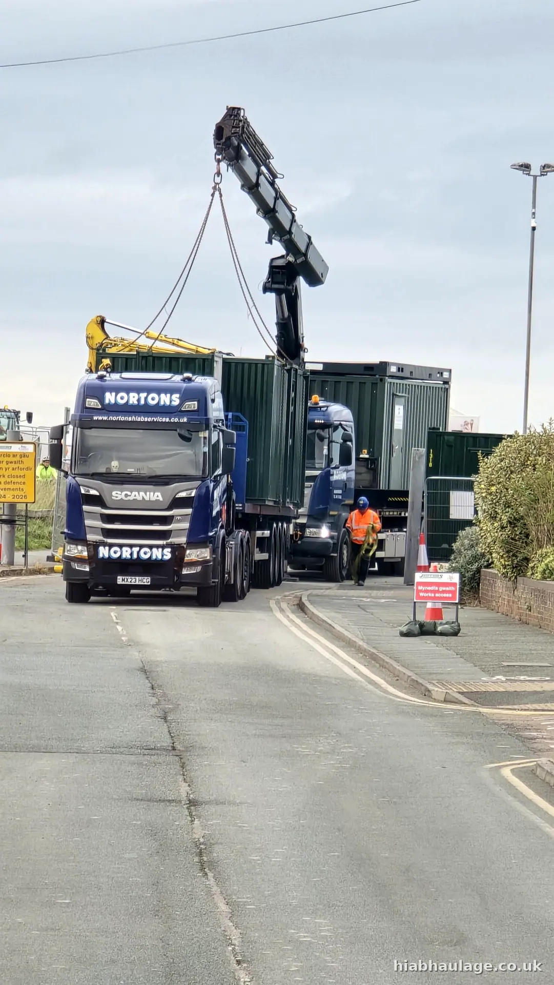 Scania HIAB lifting a green unit at a roadside site Scania HIAB lifting a green unit at a roadside site