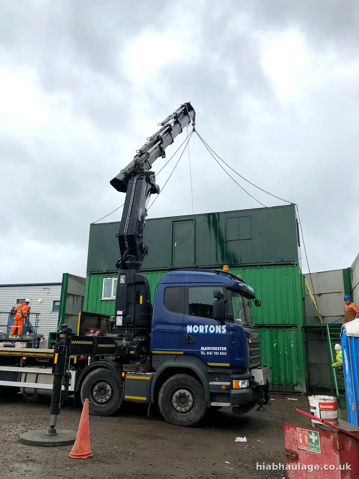 Scania HIAB lorry lifting a portable cabin at a waste site