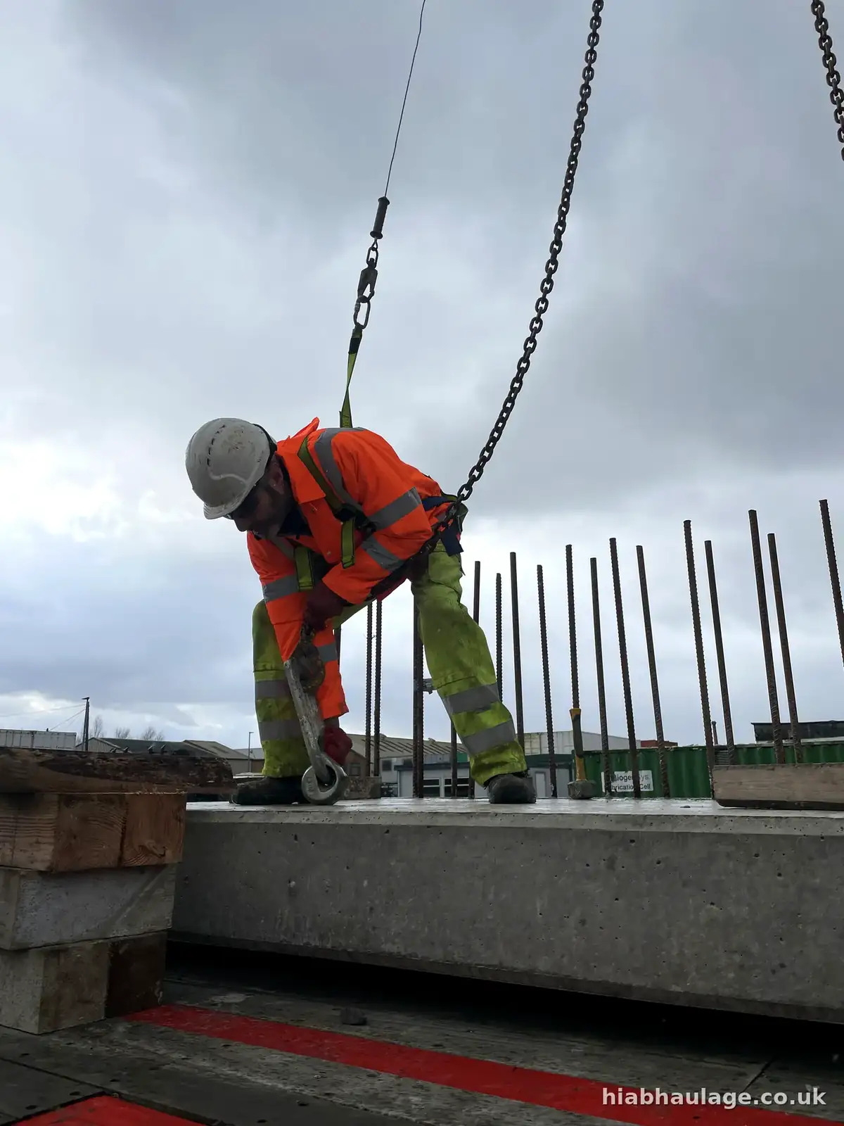 Slinger hooking lifting chains onto a precast concrete unit, close up Slinger hooking lifting chains onto a precast concrete unit, close up