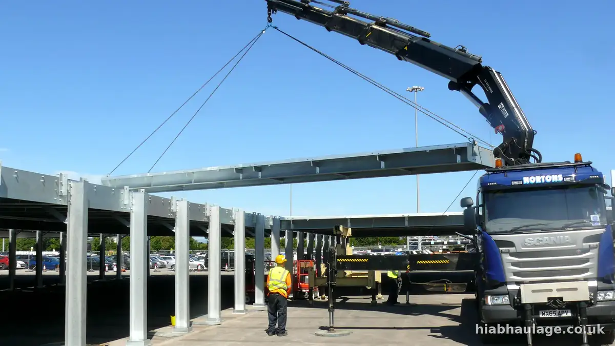 Long steel canopy beam swung into place over columns at an airport car park Long steel canopy beam swung into place over columns at an airport car park