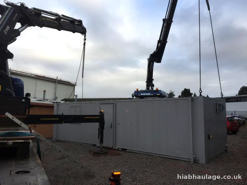 Two HIABs lifting a unit into a compound