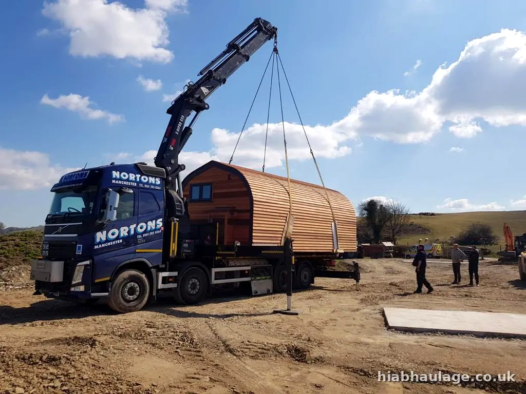 Volvo HIAB lifting a timber glamping pod on a sunny site Volvo HIAB lifting a timber glamping pod on a sunny site