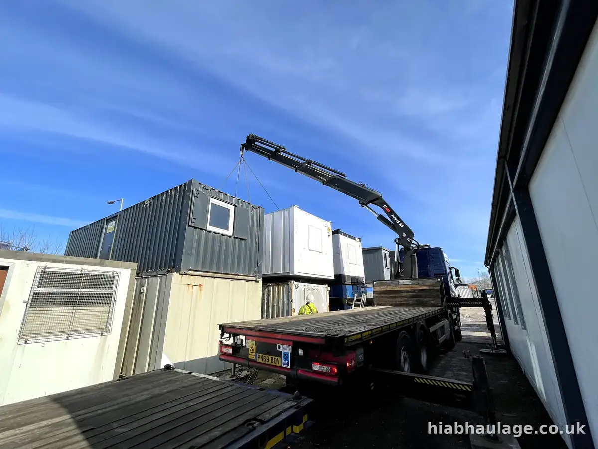 Wagon and drag HIAB placing a cabin onto its drag trailer